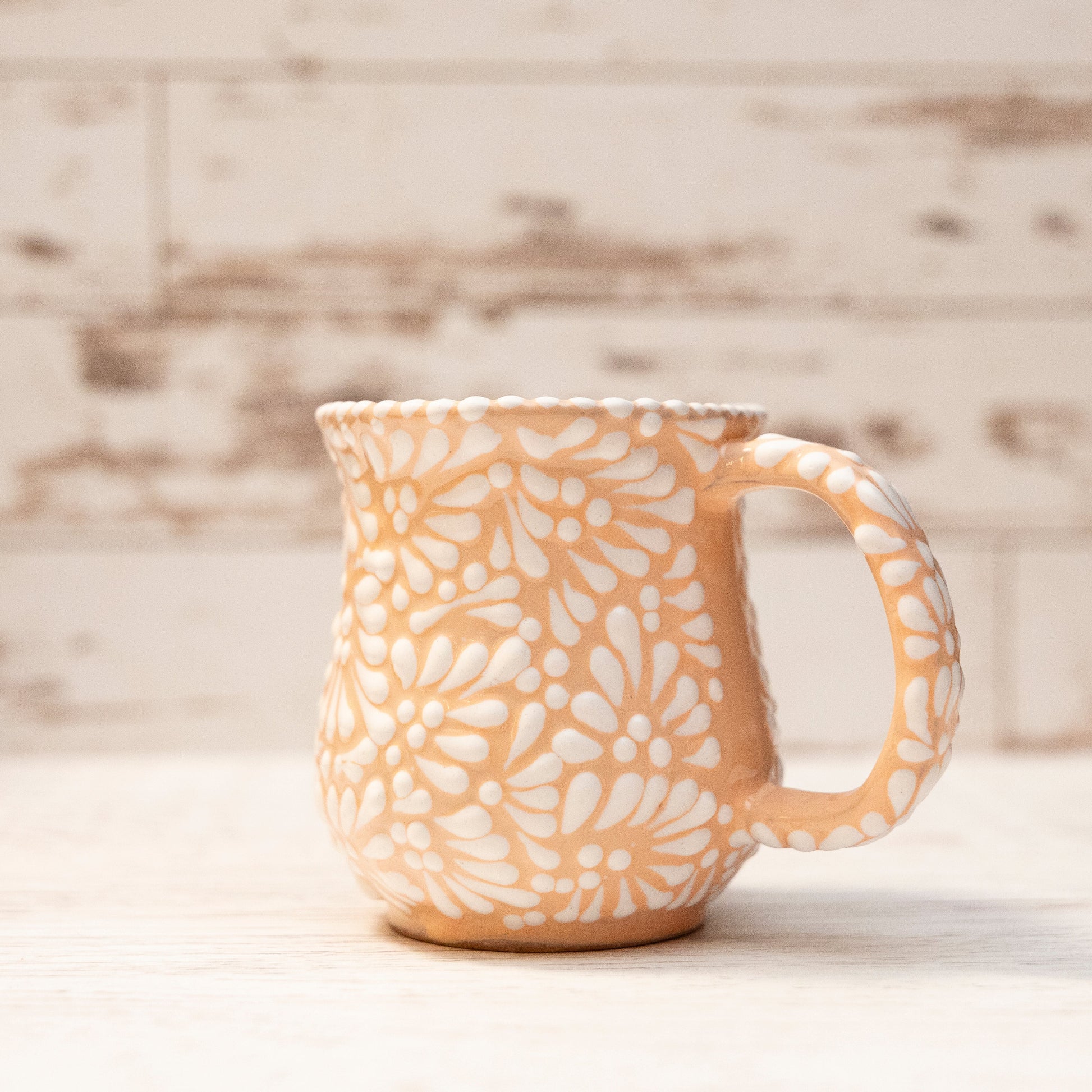 Ceramic mug with white floral pattern on a wooden surface