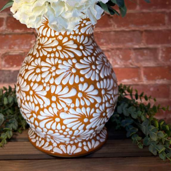 Decorative vase with floral arrangement against a brick wall