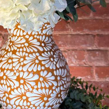 Decorative vase with white flowers against a brick wall
