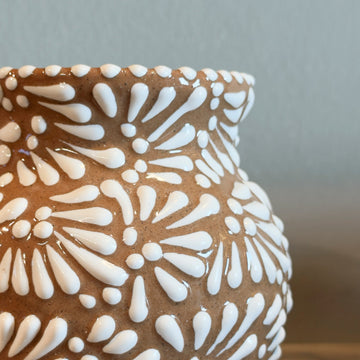Ceramic vase with white floral patterns on a wooden surface