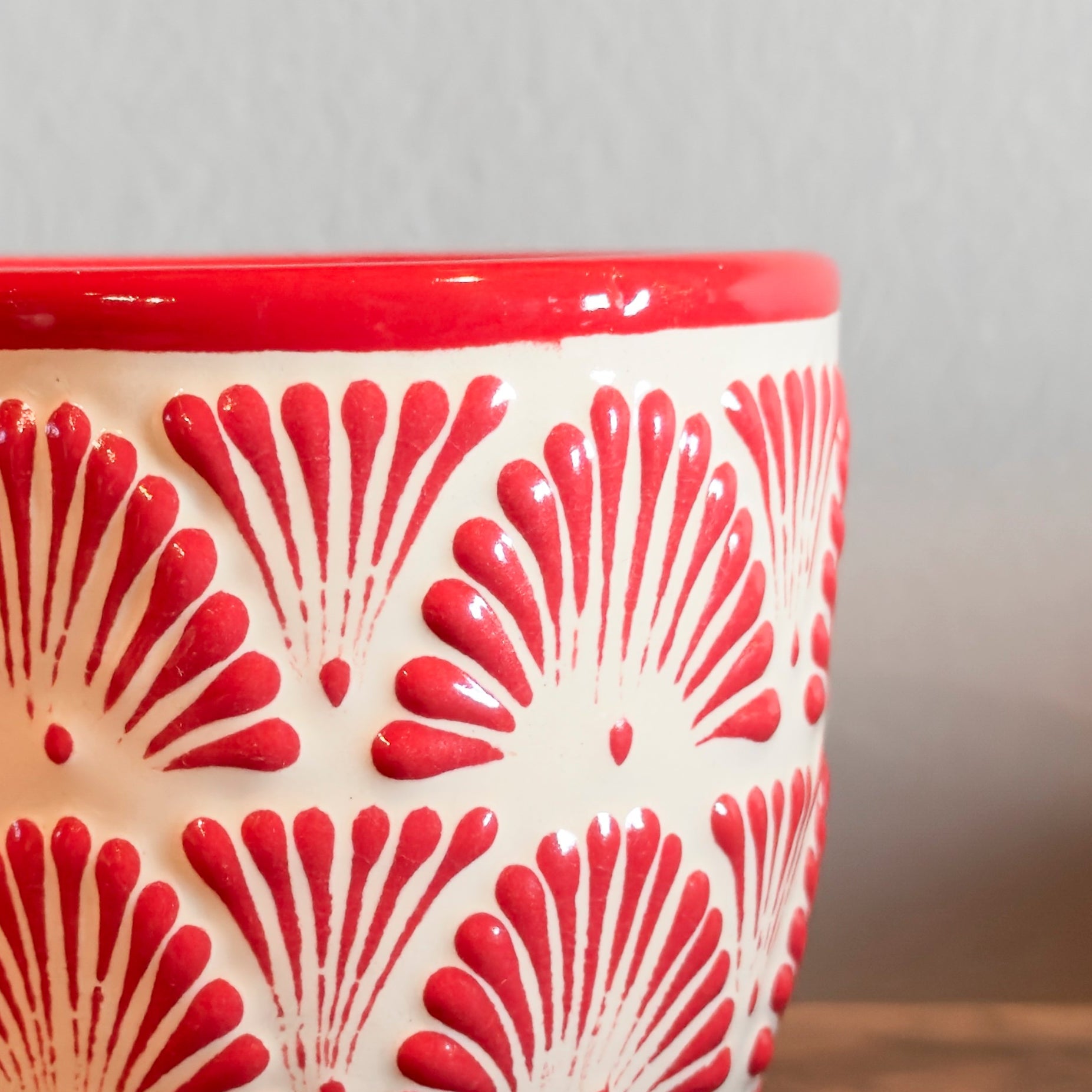 Ceramic cup with red and white pattern on a wooden surface
