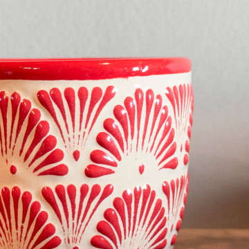 Ceramic cup with red and white pattern on a wooden surface